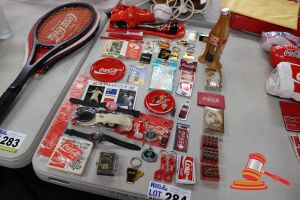 284 · BUNDLE OF ASSORTED COCA-COLA ITEMS INCLUDING: SUNGLASSES, KEYRINGS, PINS, WATCHES ETC