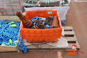 25 · 1 X ORANGE CRATE WITH HEAVY DUTY LIFTING CHAIN AND RIGGING EQUIPMENT, INCLUDES: LARGE RUSTED SHACKLES, MULTIPLE BLUE LIFTING SHACKLES, HESWA ALLOY SLING GRADE V(100) WITH TAG, VARIOUS CHAINS (SOME RUST / WORN) + 2 x DRILL BIT HEADS ON PALLET